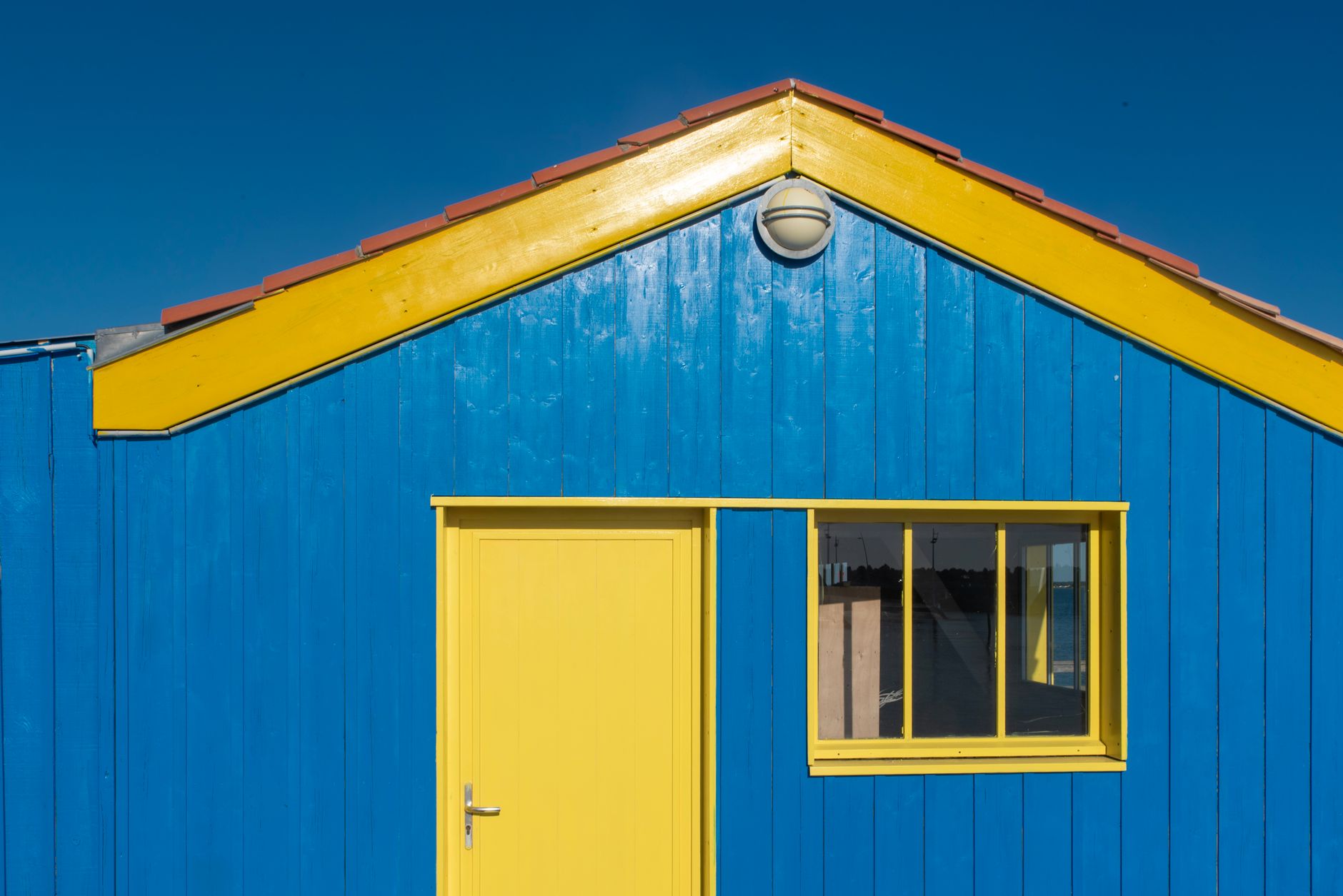 A striking blue and yellow wooden beach house against a clear blue sky
